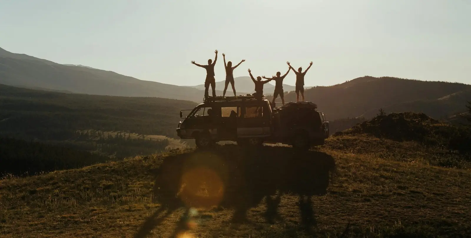 Small group of travellers standing on a vehicle at sunset